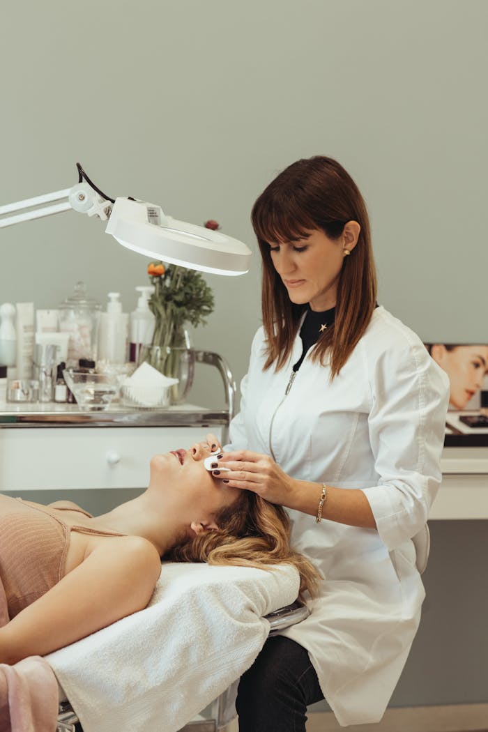 A cosmetologist performing skincare procedures on a client in a salon setting.